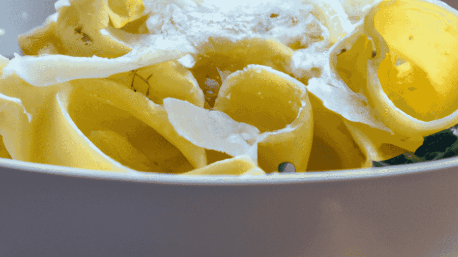 A steaming bowl of homemade pasta with fresh herbs and parmesan cheese sprinkled on top.