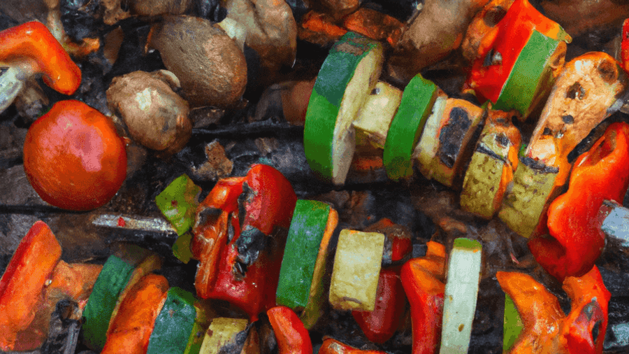 An image of a campfire with skewers of grilled veggies and meat cooking over the flames.